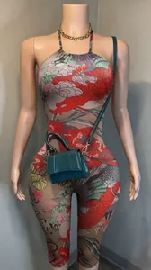 Detailed view of women's halter neck jumpsuit with vibrant Oriental print and green bag.