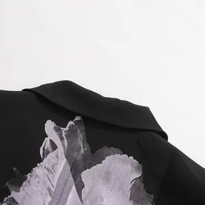 Close-up of artistic floral print on black blazer collar, premium fabric detail.