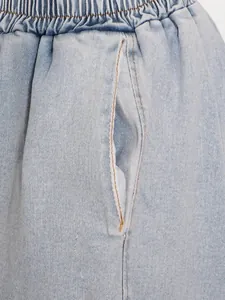 Close-up detail of elastic waistband and side pocket on casual light blue denim