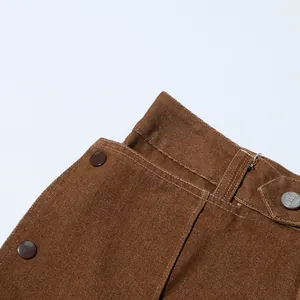Dettaglio del tessuto denim marrone vintage con bottone argento e passante per cintura