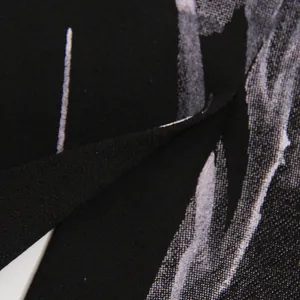 Close-up macro detail showing the refined texture and white abstract print of the black fabric