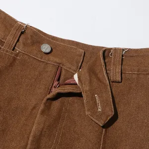 Dettaglio vita di pantaloni in denim marrone vintage con bottone e cerniera lampo