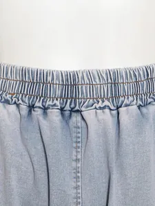 Close-up detail of the gathered elastic waistband on light wash denim shorts for women