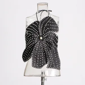 Detailed view of black halter top with pearl embellishments and petal design on clear mannequin.
