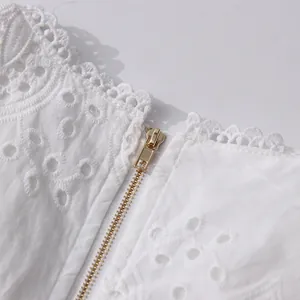 Detail shot of the golden metal zipper on a white French vintage lace embroidered top
