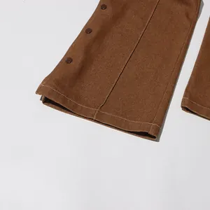 Dettaglio dell'orlo monopetto sui pantaloni dritti marroni vintage effetto consumato.