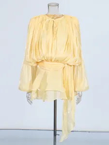 Elegant yellow pleated puff sleeve dress with waist tie and ruffle details.