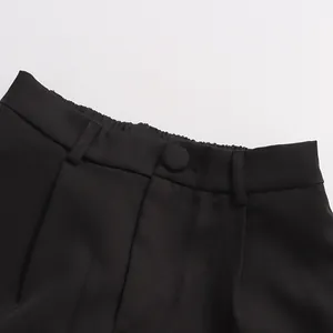 Detail shot of the elasticated waist and fabric-covered button of black straight trousers