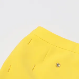 Detailed view of yellow skirt with elegant pearl lines and rhinestone embellishments.