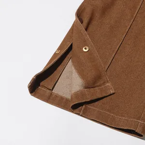 Dettaglio dell'orlo di un pantalone rétro marrone con bottoni a pressione e spacco