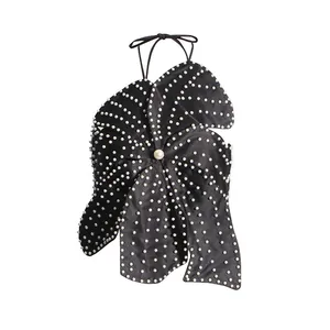 Macro detail of intricate white pearl beadwork on a black petal-shaped halter neck top