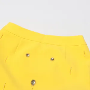 Close-up of yellow high-waist skirt with pearl beading and sparkling rhinestones
