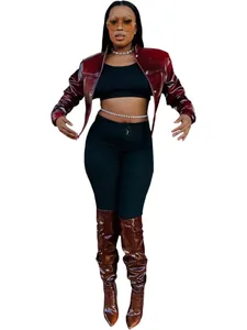 Chic burgundy patent leather cropped jacket worn by model with matching high boots.