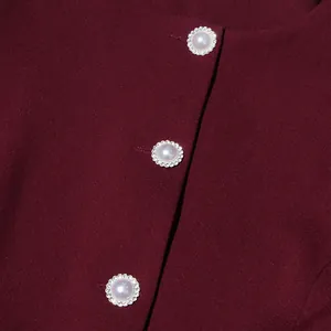 Close-up detail of faux pearl buttons with rhinestone trim on a burgundy vintage top