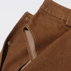 Dettaglio giacca in denim marrone vintage con bottoni a pressione dorati e cuciture.