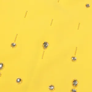 Close-up of elegant beaded and rhinestone details on bright yellow fabric