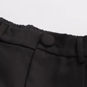 Close-up detail of high-quality black straight trousers waistband with fabric button.