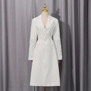 Detail eines weißen mittellangen Trenchcoats mit 3D-Blumenspitzenärmeln an einer Puppe.