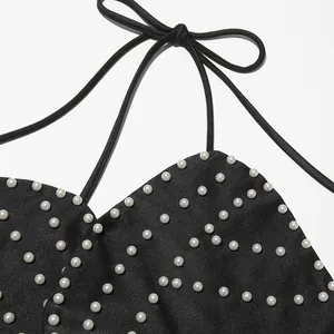 Macro detail view of heavy pearl embroidery on a black halter neck strapless top