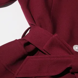 Close-up of burgundy French vintage top with belt detail and decorative pearl button.