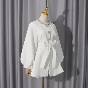 Detail view of an elegant white coat with a crystal collar and puff sleeves