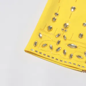 Close-up of intricate beadwork and rhinestone detailing on a yellow designer garment