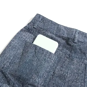 Detail van de achterzak van een blauwe casual uitlopende broek met een telefoon