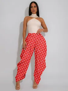 Full length view of stylish red polka dot high-waisted balloon trousers on a model.