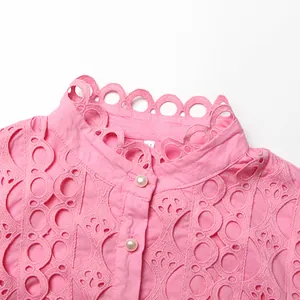 Close-up of pink hollowed-out lace top with scalloped collar and pearl buttons.