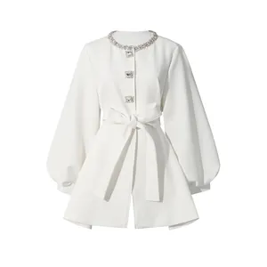 Detail showing the rhinestone embellished neckline and waist-tie of the white jacket.