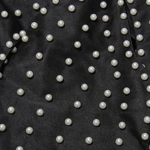 Close-up detail of white pearls on black satin fabric for a sexy halter top design