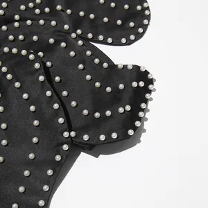 Close-up of elegant black fabric with intricate heavy pearl bead embellishments