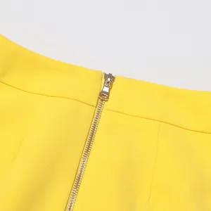 Detailed close-up of gold metal zipper on bright yellow high-waisted skirt detail