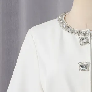 Close-up of elegant white jacket with sparkling rhinestone collar and square buttons
