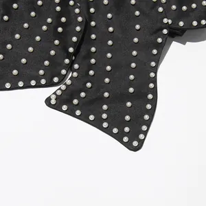 Close-up detail of heavy pearl beadwork on black fabric strap for women's halter top.