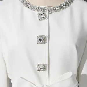 Detailed close-up of elegant white women's jacket featuring a rhinestone collar and crystal buttons