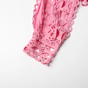Detailed close-up of pink hollow-out lace embroidery on dress cuff with scalloped edge
