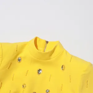 Close-up detail of a yellow high-neck top featuring elegant rhinestones and beadwork accents