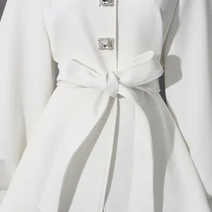 Detail view of a white elegant coat featuring diamond square buttons and a tied waist belt
