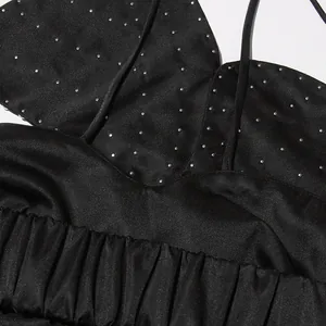 Detail view of a black halter top with heavy rhinestone beadwork and ruffled hem