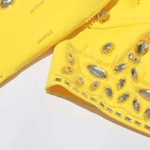 Close-up detail of intricate yellow beadwork and clear rhinestones on high-end yellow garment