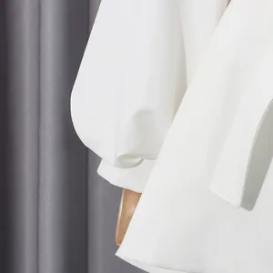 Close-up of elegant white jacket showing puff sleeves and matching waist belt detail