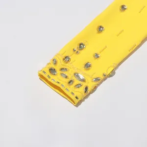 Close-up detail of luxury yellow sleeve with intricate crystal beadwork and rhinestones