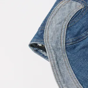 Dettaglio del top in denim lavato con trama del tessuto blu e cuciture a contrasto.