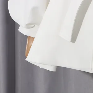 Close-up view of white puff sleeve and premium twill fabric on elegant belted jacket