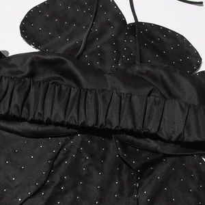 Macro detail of a black halter top with elegant rhinestone studding and satin finish