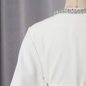 Detailed view of white elegant jacket featuring rhinestone embellished round neckline