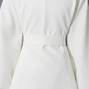 Detailed view of elegant white coat waist design featuring a matching fabric tie belt