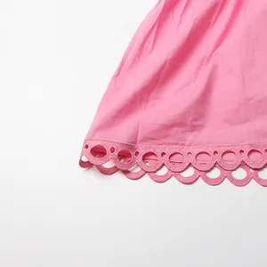 Close-up of pink dress hem featuring delicate scalloped eyelet lace embroidery