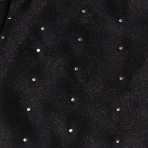 Macro detail of heavy beadwork and silver studs on black fabric top